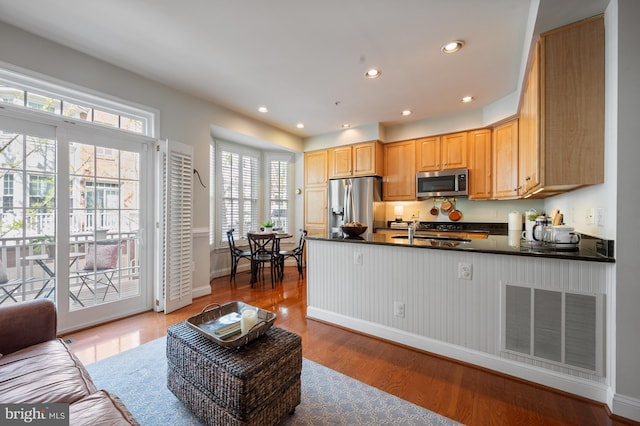 kitchen with dark countertops, a sink, stainless steel appliances, a peninsula, and visible vents