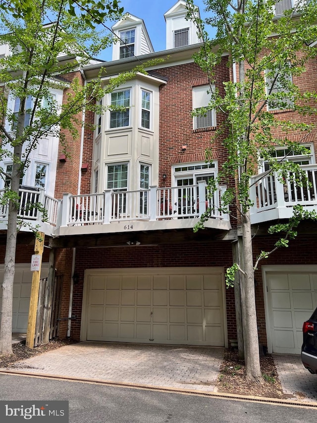 exterior space featuring brick siding, driveway, a balcony, and a garage