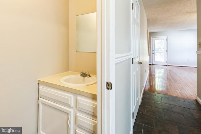 bathroom featuring vanity, baseboards, and a textured ceiling