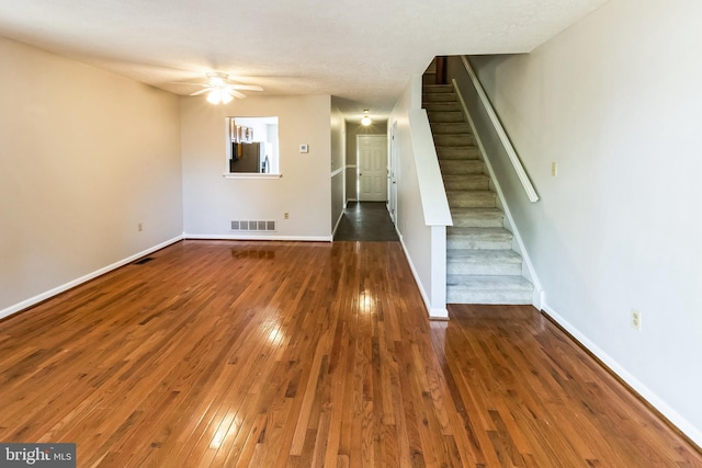 unfurnished living room featuring visible vents, baseboards, stairs, a ceiling fan, and wood-type flooring