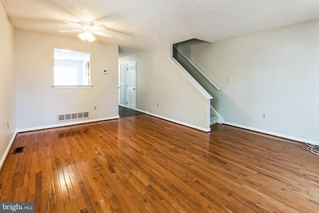 unfurnished living room with visible vents, baseboards, stairs, and hardwood / wood-style flooring