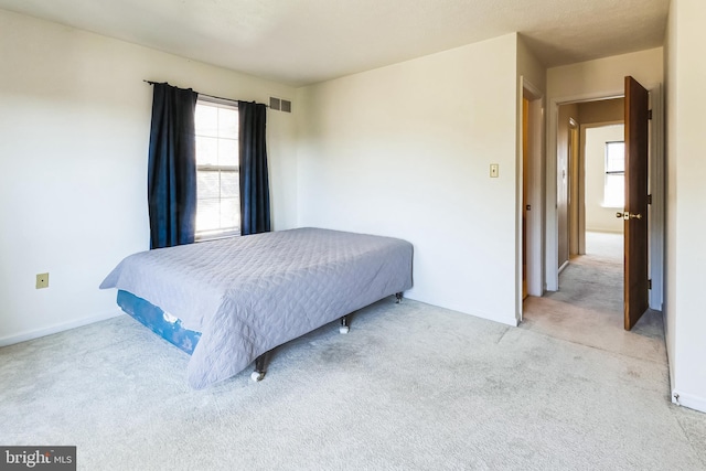 bedroom with light carpet, visible vents, and baseboards