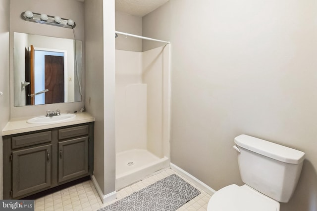 bathroom with vanity, toilet, baseboards, and a stall shower