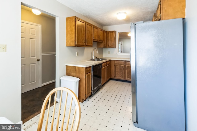 kitchen featuring light floors, freestanding refrigerator, a sink, light countertops, and dishwasher