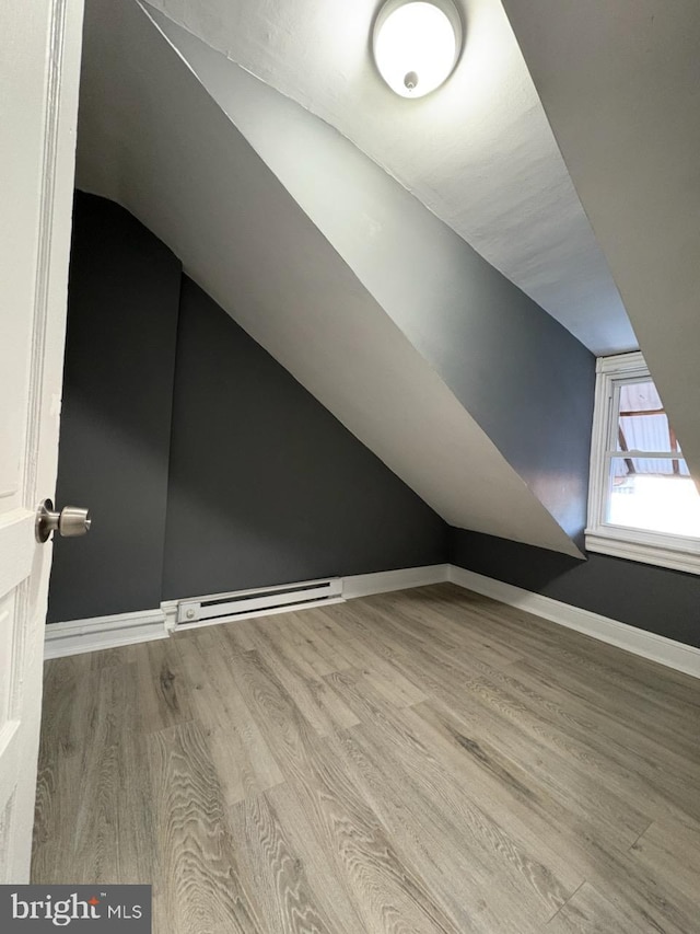 additional living space featuring baseboard heating, lofted ceiling, baseboards, and wood finished floors