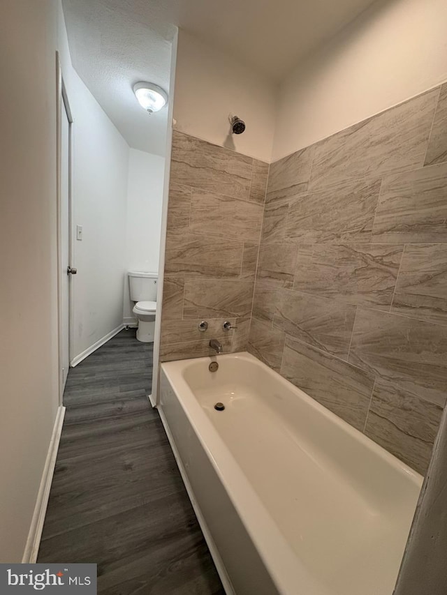 bathroom featuring toilet, shower / tub combination, baseboards, and wood finished floors