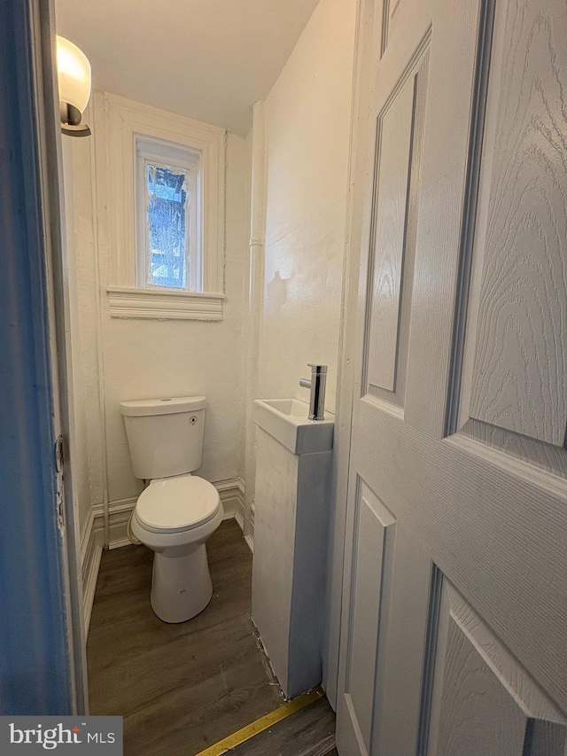 bathroom featuring a sink, baseboards, toilet, and wood finished floors