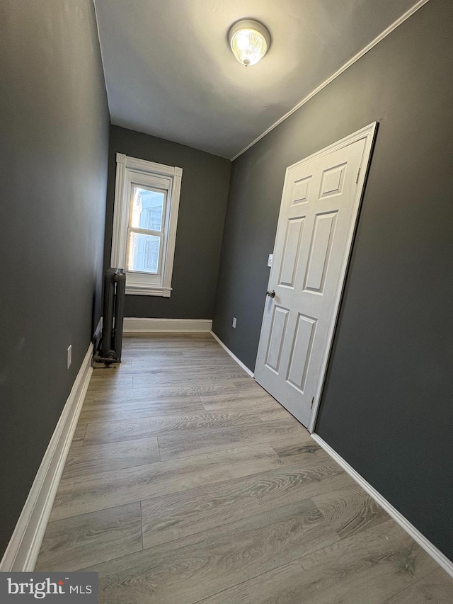 empty room with radiator heating unit, baseboards, and wood finished floors