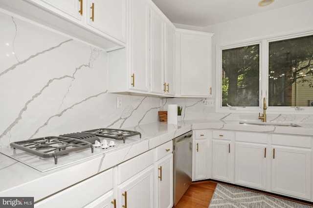 kitchen featuring a sink, backsplash, white gas cooktop, white cabinetry, and stainless steel dishwasher