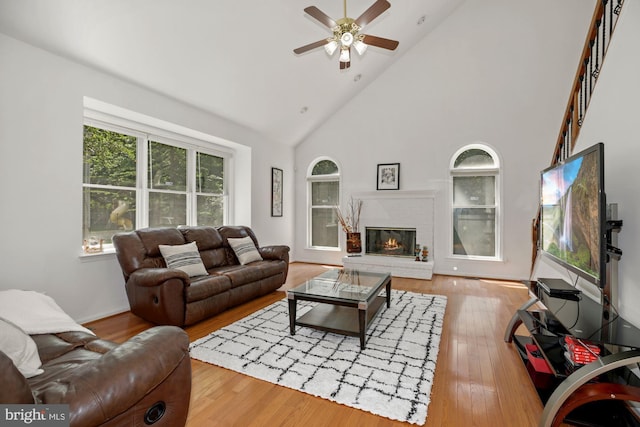 living area featuring hardwood / wood-style flooring, high vaulted ceiling, a fireplace, and ceiling fan