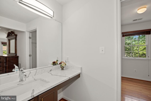 bathroom featuring visible vents, baseboards, wood finished floors, and vanity