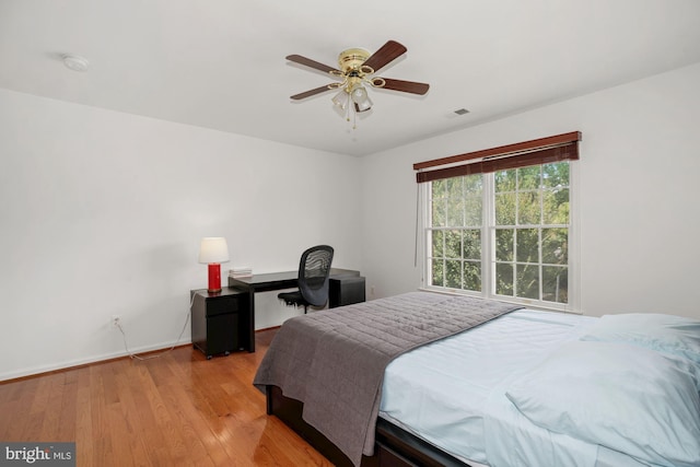 bedroom featuring light wood finished floors, visible vents, a ceiling fan, and baseboards