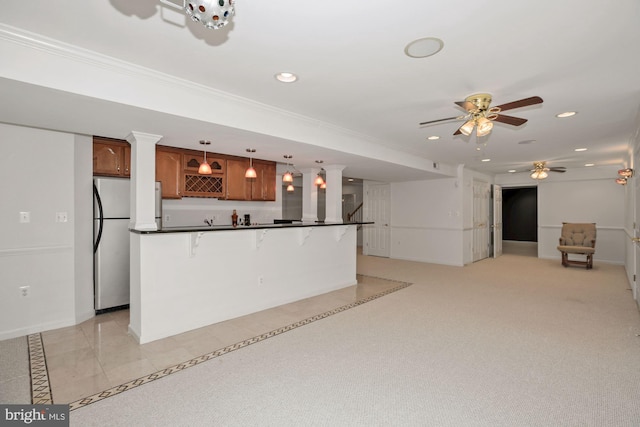 kitchen featuring recessed lighting, brown cabinets, dark countertops, and freestanding refrigerator