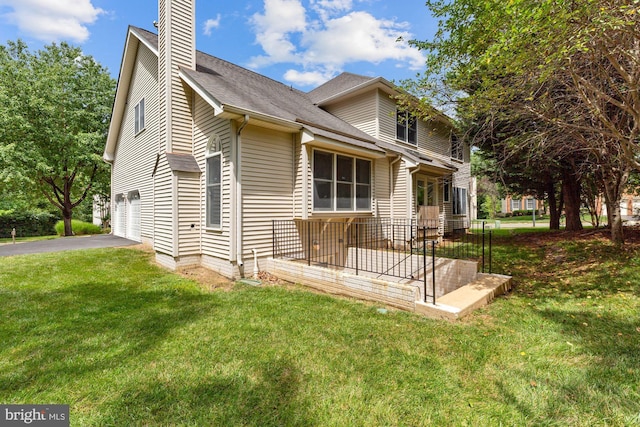 view of front of house featuring a front yard, an attached garage, a chimney, and aphalt driveway