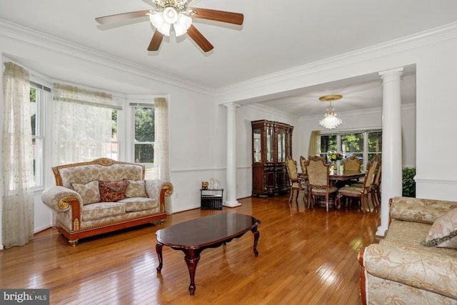 living room featuring wood-type flooring, crown molding, and ornate columns