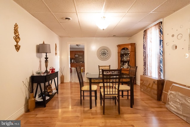 dining area with baseboards, a paneled ceiling, visible vents, and light wood-type flooring