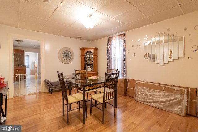 dining space with light wood-style flooring and a paneled ceiling