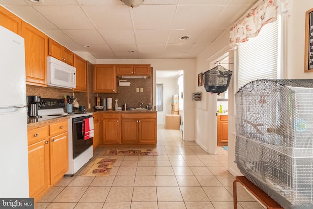 kitchen with light tile patterned floors, decorative backsplash, a healthy amount of sunlight, and white appliances