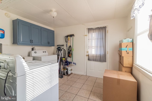 laundry room featuring a healthy amount of sunlight, light tile patterned flooring, cabinet space, and washing machine and clothes dryer