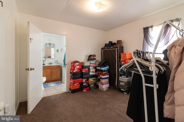 bedroom featuring light carpet, ensuite bath, and a sink