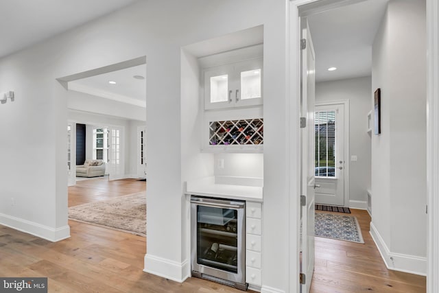 interior space with beverage cooler, recessed lighting, light wood-style floors, baseboards, and a dry bar