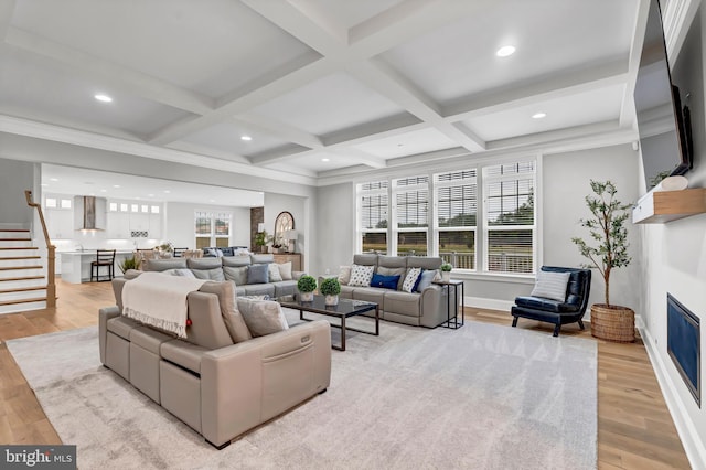 living area with beam ceiling, coffered ceiling, and light wood-style flooring