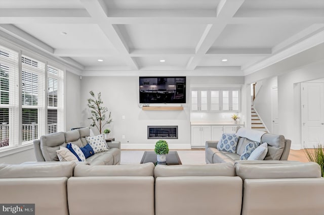 living room with a glass covered fireplace, light wood-style flooring, stairs, and baseboards