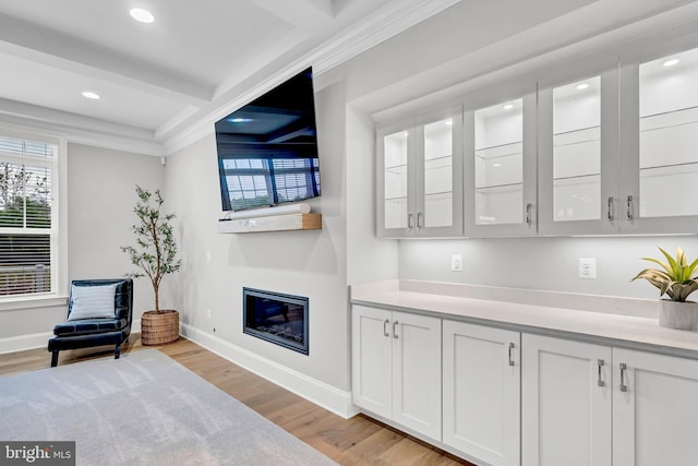 living area featuring a glass covered fireplace, recessed lighting, light wood-type flooring, and baseboards