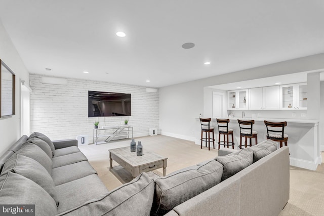 living area featuring recessed lighting, light carpet, and brick wall