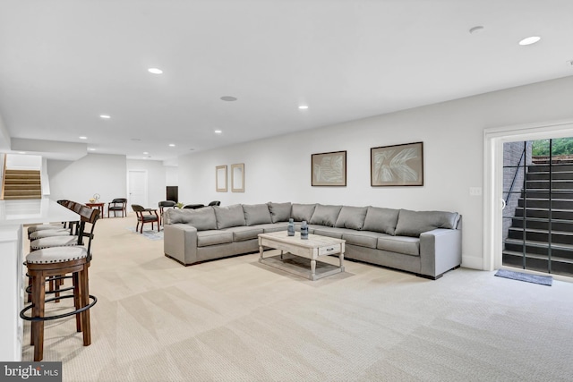 living room with stairs, recessed lighting, and light colored carpet