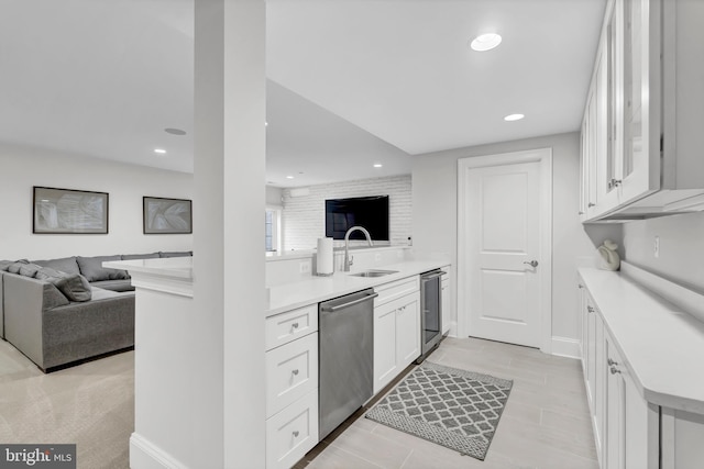 kitchen featuring a sink, light countertops, white cabinets, dishwasher, and open floor plan