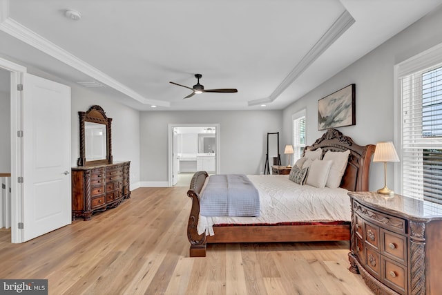 bedroom featuring a ceiling fan, baseboards, a tray ceiling, light wood-style flooring, and ornamental molding