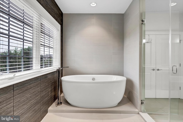 bathroom with a freestanding bath, tile walls, and a shower stall