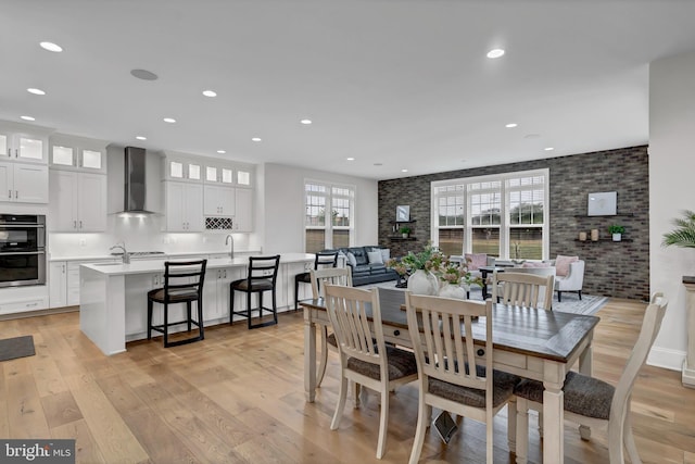 dining space with recessed lighting, brick wall, and light wood-type flooring