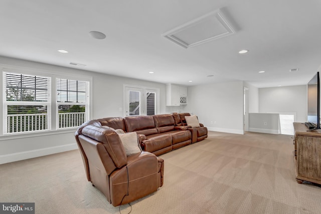 living room with visible vents, baseboards, light colored carpet, and attic access