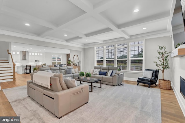 living area featuring coffered ceiling, a fireplace, and light wood-type flooring