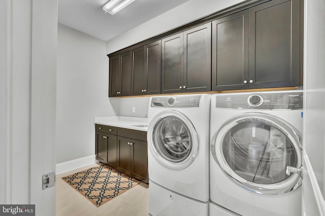 laundry room featuring washing machine and clothes dryer, cabinet space, and baseboards