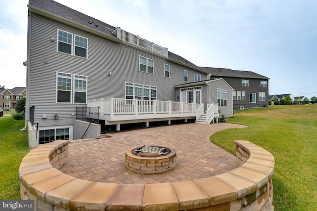 rear view of property featuring a deck, a patio, and a lawn