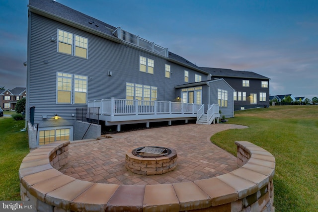 back of property with a lawn, a deck, an outdoor fire pit, and a patio area