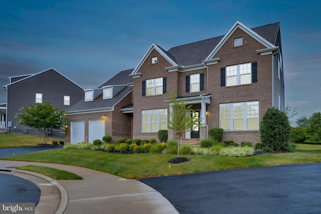 view of front of house featuring brick siding, driveway, a front yard, and a garage