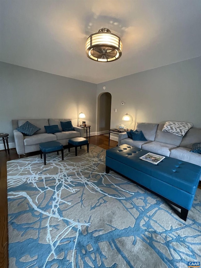 living room featuring wood finished floors, arched walkways, and baseboards