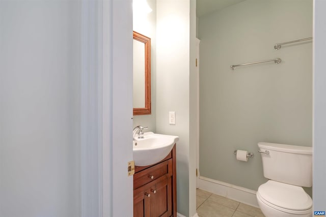 half bath featuring tile patterned flooring, toilet, vanity, and baseboards