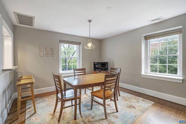 dining space with wood finished floors, visible vents, and baseboards