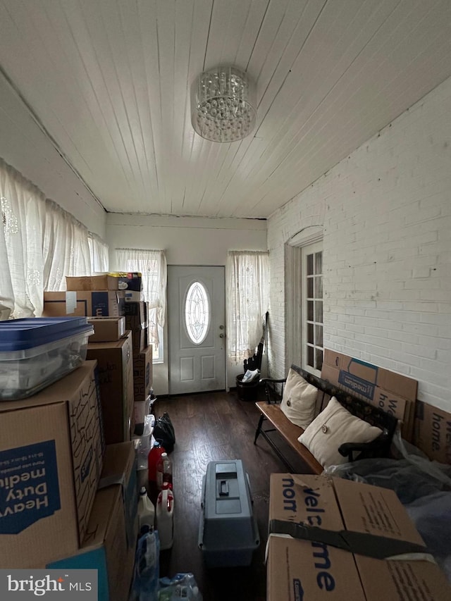 interior space featuring wood ceiling, wood finished floors, and brick wall