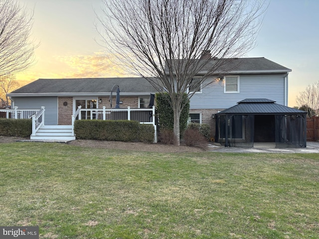 back of house with a gazebo, a lawn, and brick siding