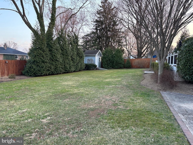 view of yard featuring an outbuilding, a shed, and fence private yard