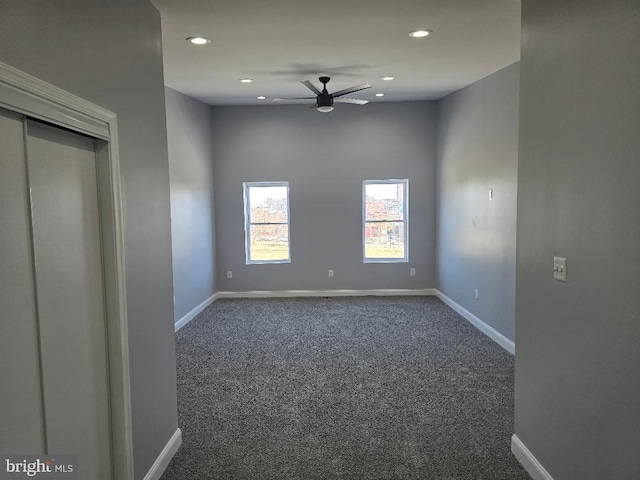 unfurnished room featuring dark carpet, baseboards, and ceiling fan