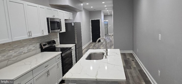 kitchen featuring a sink, wood finished floors, appliances with stainless steel finishes, white cabinets, and decorative backsplash