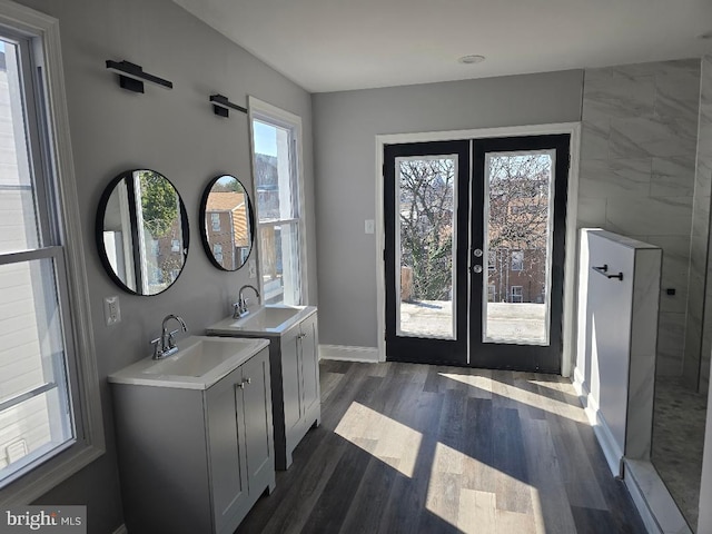 full bathroom featuring a sink, french doors, two vanities, and wood finished floors