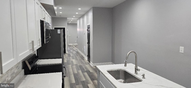 corridor featuring a sink, baseboards, wood finished floors, and recessed lighting